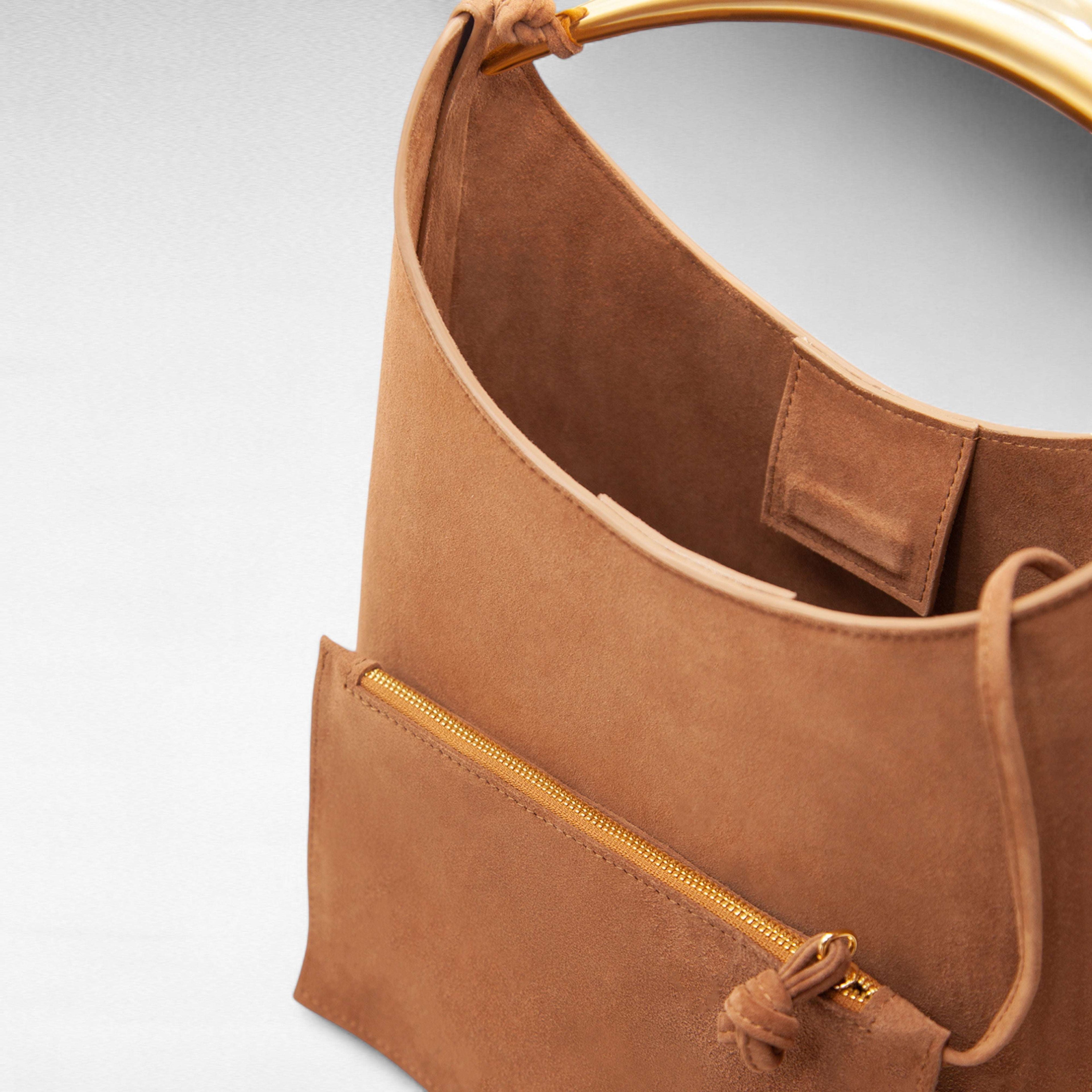 Brown suede handbag with sculptural gold handle and small zip pouch